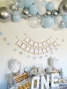 a table topped with balloons and desserts next to a sign that says one above it