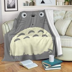 a totoro blanket sitting on top of a wooden floor next to a couch