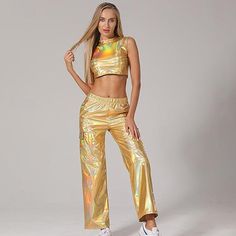 a woman in gold pants and crop top posing for the camera