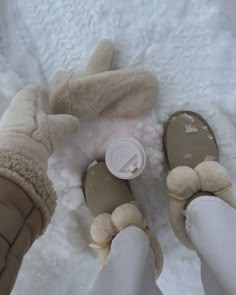 someone is wearing slippers and holding a cup in their hand while standing on the snow