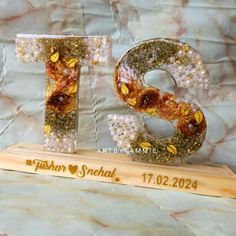 the letters are made out of glass beads and gold leafy decorations on top of a wooden stand