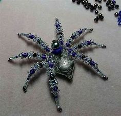 a silver and blue spider brooch sitting on top of a table next to beads