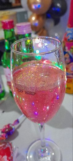 a wine glass filled with pink liquid on top of a table next to candy bars