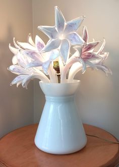 a white vase filled with flowers on top of a wooden table