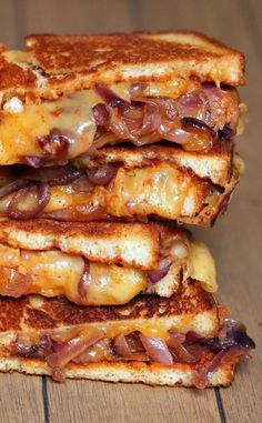 two grilled cheese sandwiches stacked on top of each other with onions and melted cheese