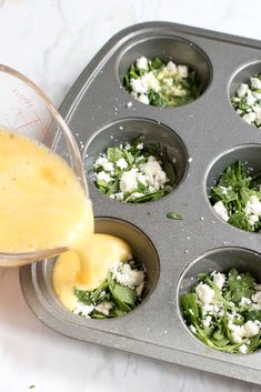 someone pouring dressing into a muffin tin filled with spinach and feta cheese