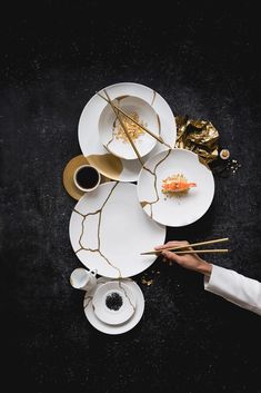 a person holding chopsticks over plates with food on them