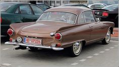 an old car is parked on the side of the road in front of other cars