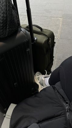 two pieces of luggage sitting on the ground next to a person's feet and hand