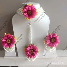 pink flowers and pearls are on display in front of a white mannequins