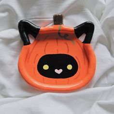 an orange plastic plate with a black cat on it's face and eyes painted onto the surface