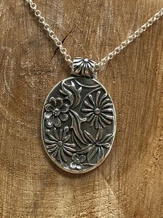 This gorgeous pendant is crafted using Fine Silver.  It features an array of flowers and leaves in an oval shape.  This pendant hangs on a 24inch Sterling Silver small Rolo chain. Elegant Stamped Flower Pendant Necklaces, Elegant Stamped Flower Pendant Necklace, Nature-inspired Oval Jewelry With Large Pendant, Artisan Oval Necklaces, Silver Oval Jewelry With Flower Charm, Nature-inspired Necklace With Large Oval Pendant, Artisan Oval Engraved Necklace, Artisan Engraved Oval Necklace, Silver Stamped Oval Pendant Necklace