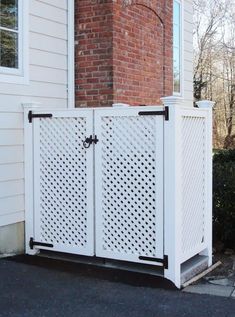 a white gate sitting in front of a house next to a brick wall and window