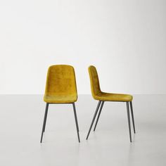 two yellow chairs sitting next to each other on top of a white floor with black legs