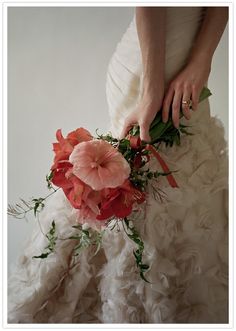 a woman in a wedding dress holding a bouquet of flowers with her hands on it