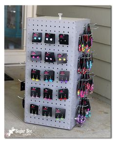 a rack with earrings hanging on it in front of a house and the door is open