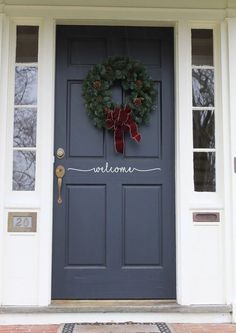 a blue front door with a welcome sign on it and a wreath hanging from the side