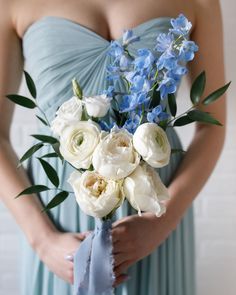 a bridesmaid holding a bouquet of white and blue flowers