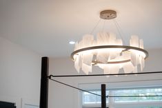 a chandelier hanging from the ceiling in a room with white walls and windows