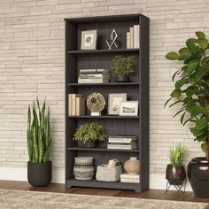 a grey bookcase sitting next to a potted plant