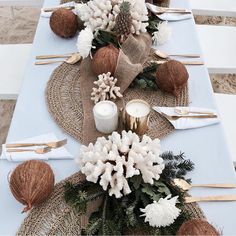 the table is set with white flowers and pine cones