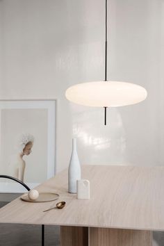 a white vase sitting on top of a wooden table next to a framed photo and lamp