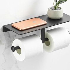 two rolls of toilet paper sitting on top of a shelf next to a cell phone