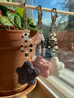 three crocheted key chains hanging from a window sill next to a potted plant