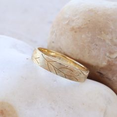 a gold ring with leaves on it sitting on top of a rock next to some rocks