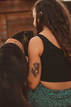 a woman with a tattoo on her arm hugging a dog