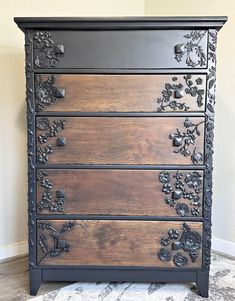 an old dresser is painted black and has flowers on it