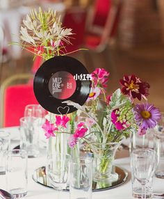 the table is set with flowers in vases and empty wine glasses on it, along with silverware