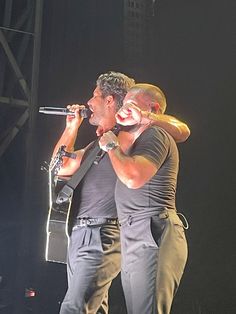 two men on stage singing into microphones