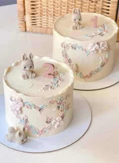 two cakes decorated with animals and flowers are on a plate next to a basket full of strawberries