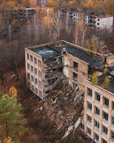 an abandoned building in the middle of a forest with lots of trees and buildings around it