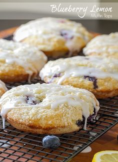 blueberry lemon muffins with icing on a cooling rack next to sliced lemons