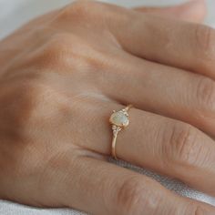 a woman's hand wearing a gold ring with an opalite and diamond