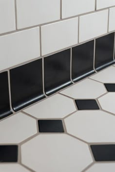 a black and white tiled bathroom floor with hexagonal tiles on the bottom half