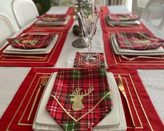 the table is set with red and green plaid napkins, silverware, and gold place settings