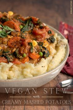 a white bowl filled with mashed potatoes and vegetables on top of a wooden table