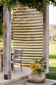 an outdoor area with a table and chairs under a pergolated trellis covered in vines