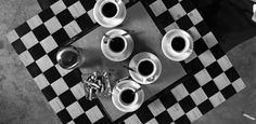 black and white photograph of coffee cups on checkered table