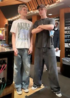 two young men standing next to each other in front of a recording equipment store counter