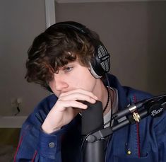 a young man wearing headphones sitting in front of a microphone