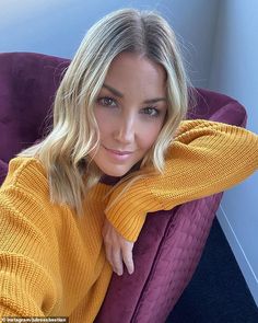 a woman sitting in a purple chair wearing a yellow sweater