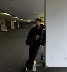 a woman leaning against the wall in an empty parking garage with her hand on her hip