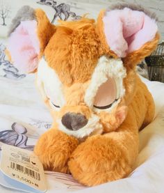 a stuffed animal is sitting on a bed with the tag in front of it's ear