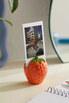 an orange figurine sitting on top of a desk next to a notepad