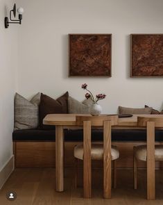 a wooden table sitting under two paintings on the wall