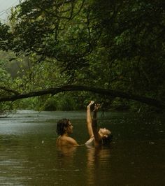 two people are in the water and one is reaching up for something